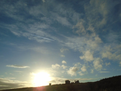 one jet plane making vapour trails across the bleak terrain