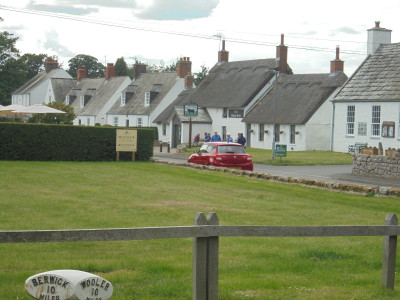 A thatched pub and an "Honesty" box charger at the back of the village hall.
